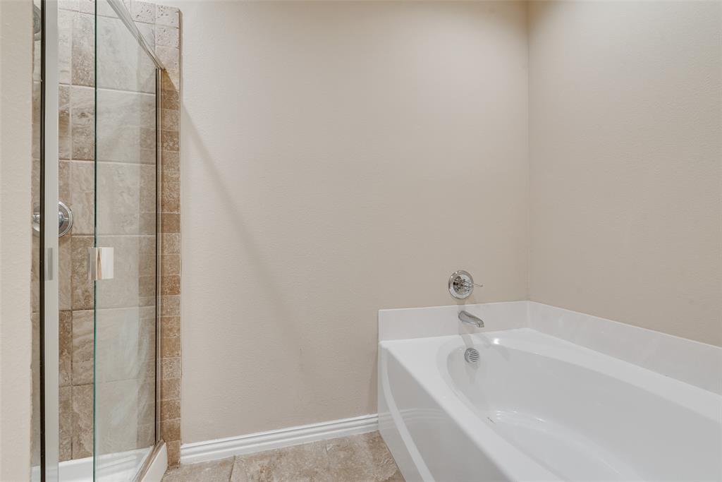 Bathtub with chrome fixtures, tiled shower surround, and glass shower enclosure