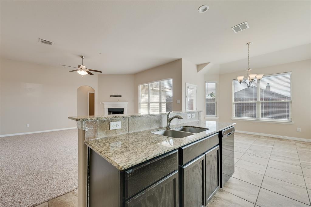 Kitchen island with granite countertops, double basin sink, and integrated dishwasher