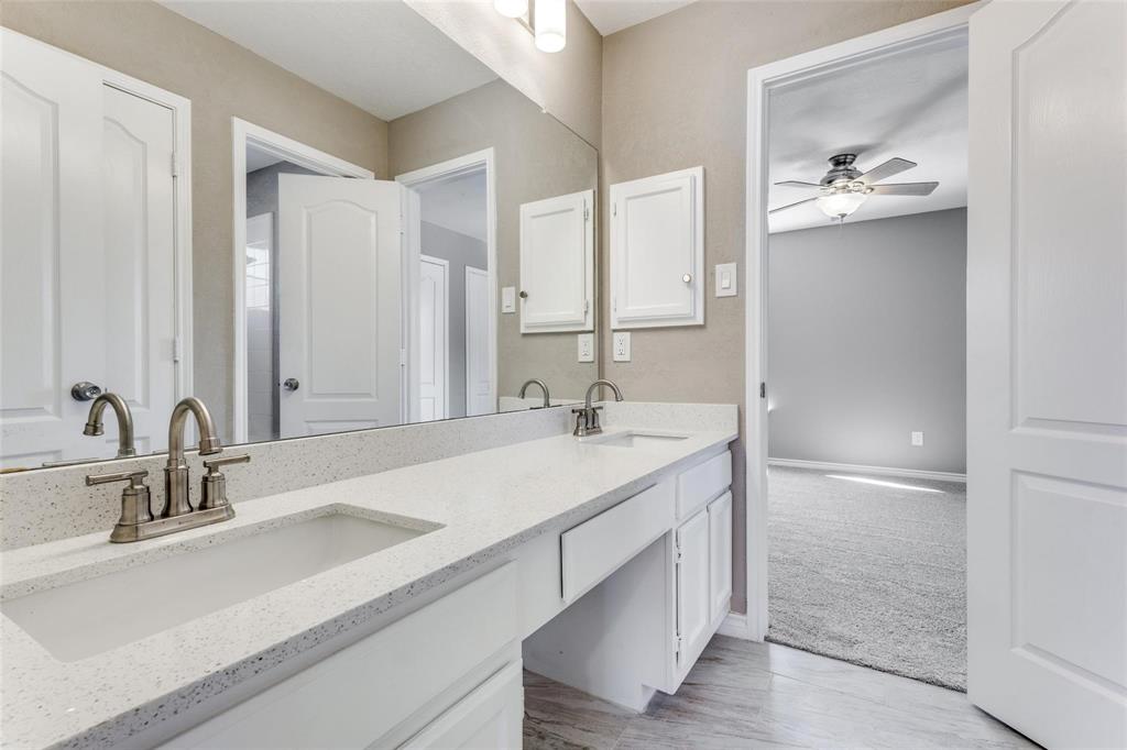 Dual vanity upstairs with integrated sinks, brushed nickel fixtures, white cabinetry, and a full-width mirror