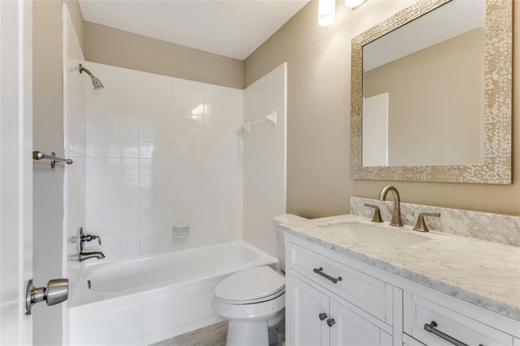 2nd full bath updstairs with stone countertop, bronze-finish faucet, and an ornate framed mirror