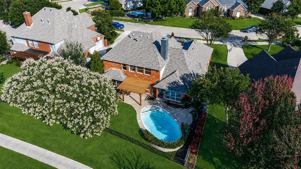 Brick exterior with a gabled roof, featuring a backyard pool, wooden pergola, and lush green lawn