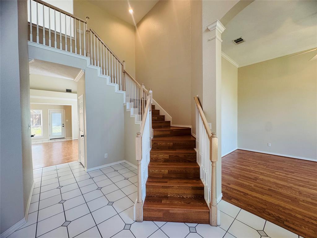 Two-story entry with a wood-finish staircase, tile flooring, and a second-story landing Two-story entry with a wood-finish staircase, tile flooring, and a second-story landing