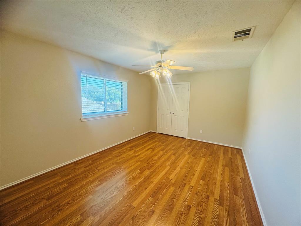 Wood-finish flooring, ceiling fan with integrated lighting, double-door closet, and window with horizontal blinds