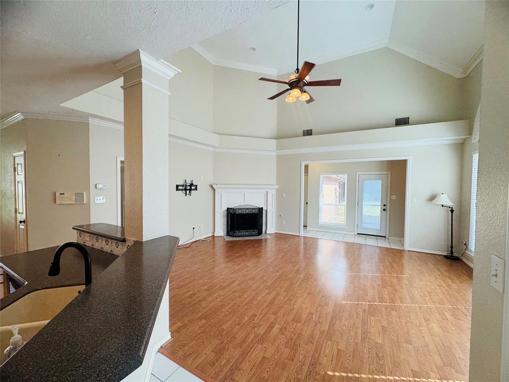 Vaulted ceiling with crown molding, wood-finish flooring, fireplace with white mantel, glass-paned exterior door, and built-in breakfast bar Vaulted ceiling with crown molding, wood-finish flooring, fireplace with white mantel, glass-paned exterior door, and built-in breakfast bar