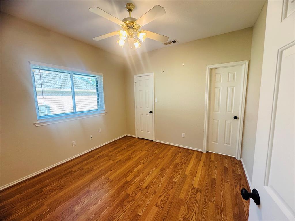 Wood-finish flooring, ceiling fan with integrated lighting, and multiple paneled doors