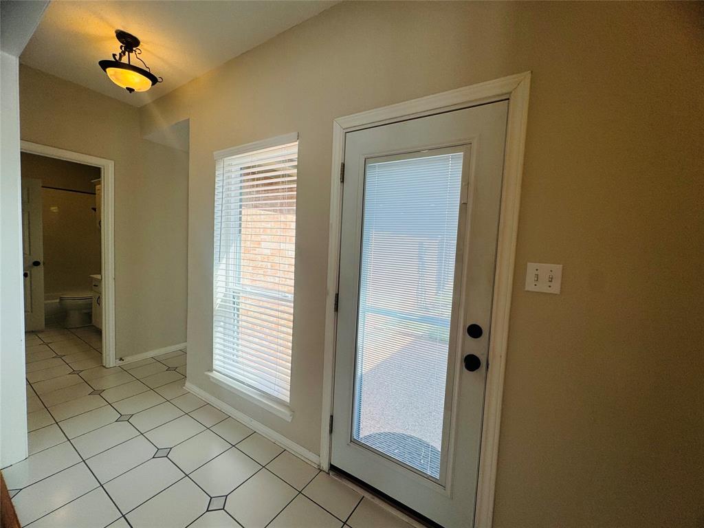Tiled flooring with decorative accents, an exterior door with integrated blinds, and a large window with horizontal blinds Tiled flooring with decorative accents, an exterior door with integrated blinds, and a large window with horizontal blinds
