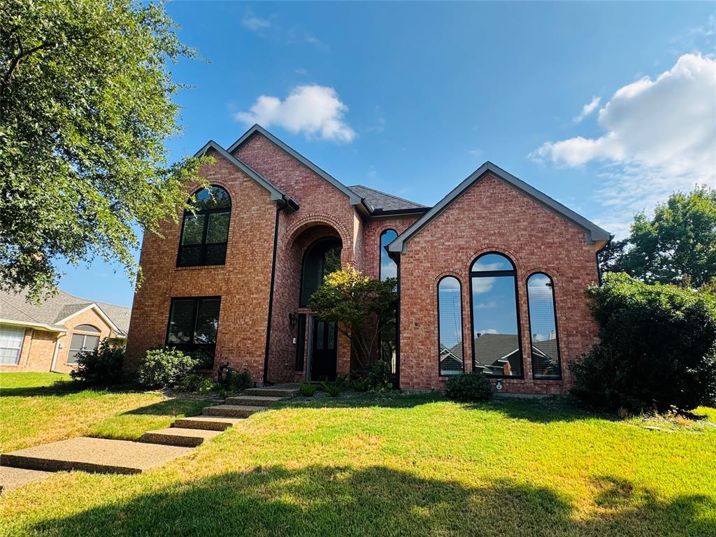 Brick facade with arched windows, prominent gables, and a concrete pathway