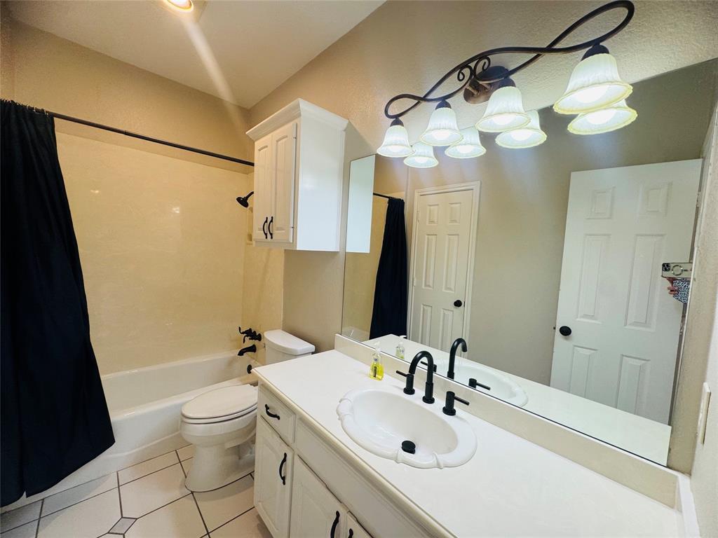 Bathroom featuring a white vanity with integrated sink, matte black faucet, wall-mounted mirror, and tile flooring Bathroom featuring a white vanity with integrated sink, matte black faucet, wall-mounted mirror, and tile flooring