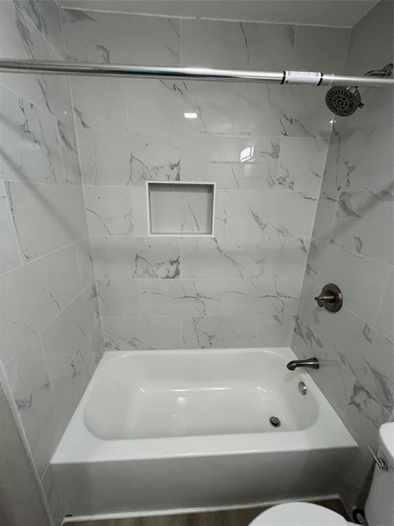 Bathtub with white subway tile surround, recessed shower niche, brushed nickel fixtures, and a chrome shower rod