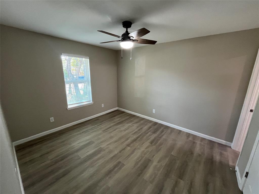 Wood-finish flooring, single window with blinds, ceiling fan with integrated lighting, and neutral wall tones