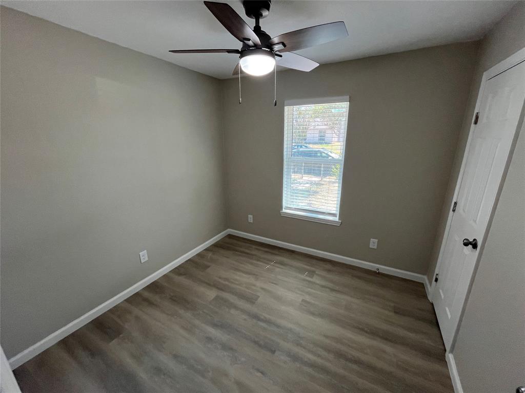 Wood-finish flooring, neutral wall tones, white trim, ceiling fan with integrated lighting, and window with blinds