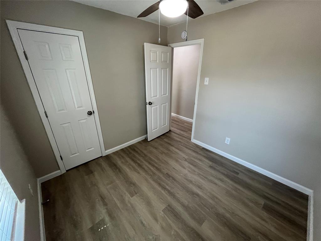Wood-finish flooring, neutral wall color, ceiling fan with integrated lighting, and white paneled doors
