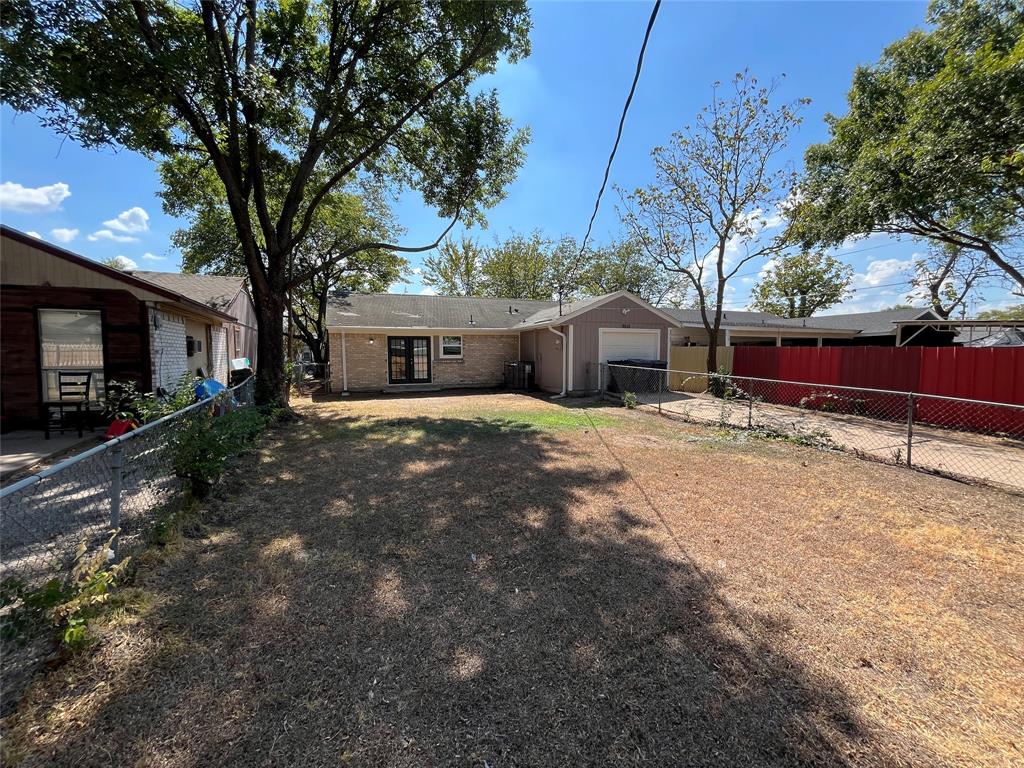 Chain link fencing enclosing the property, brick exterior, two-panel glass door, mature tree, attached garage