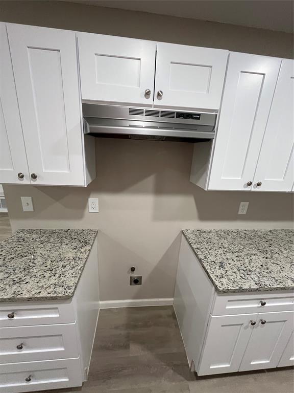 White shaker-style cabinetry, stainless steel range hood, light-toned wood-finish flooring, and granite countertops