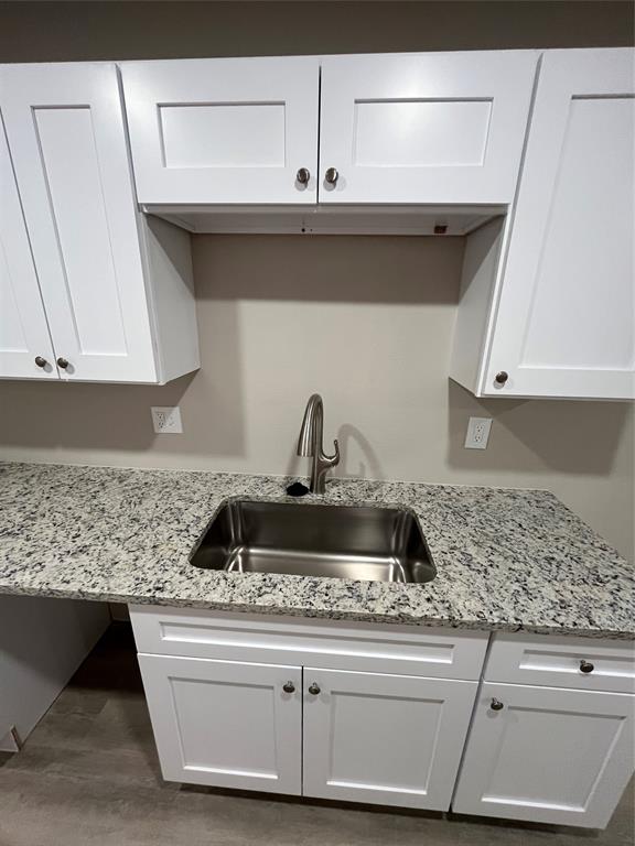 Stainless steel sink, granite-style countertop, white shaker cabinetry, and brushed nickel hardware