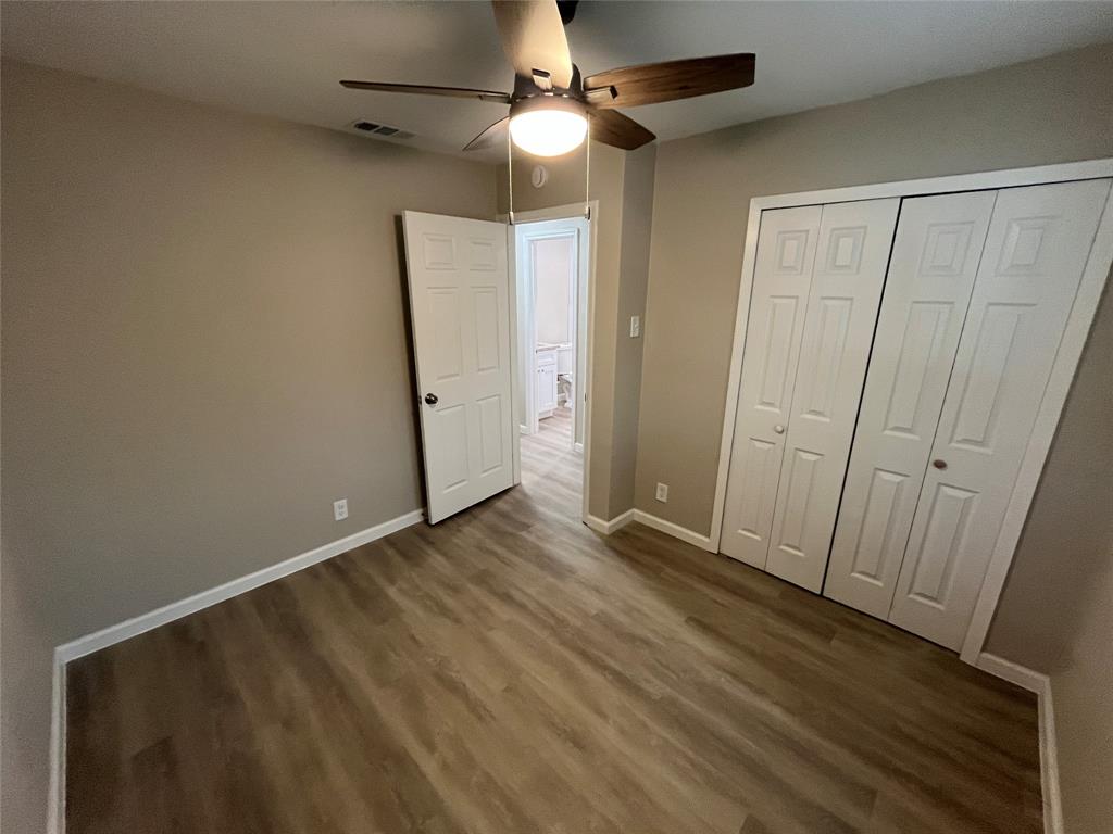 Wood-finish flooring, ceiling fan with integrated lighting, neutral wall tones, and bi-fold closet doors