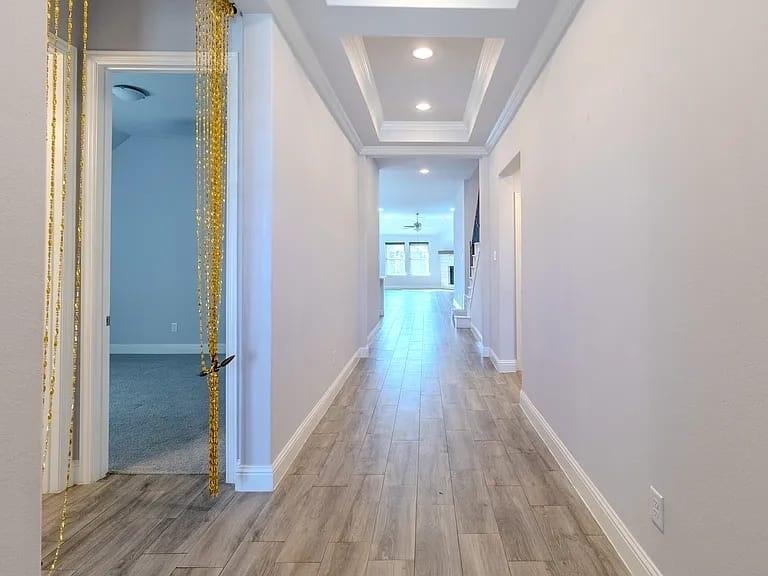 Recessed lighting, tray ceiling, wood-finish flooring, white baseboards, and white wall paint