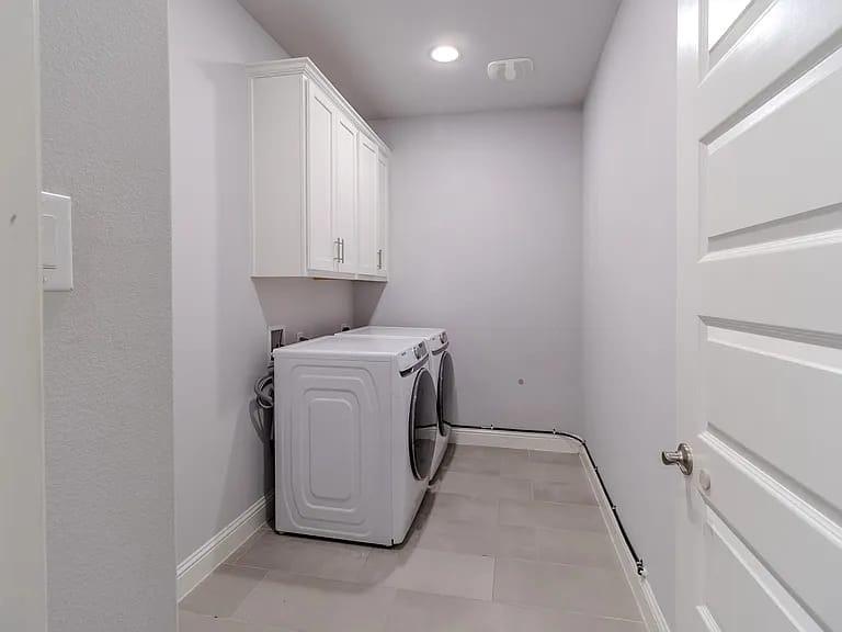 Laundry area featuring white cabinetry, a single overhead light, and a white paneled door