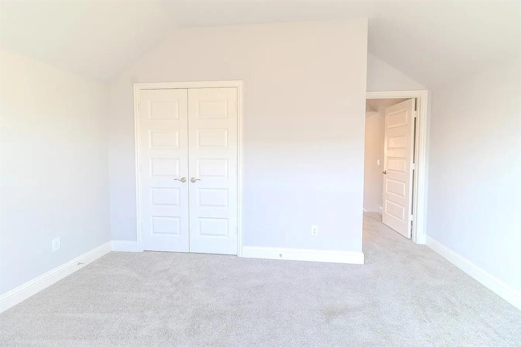 Vaulted ceiling, paneled double doors, light-toned carpeting, and crisp white trim