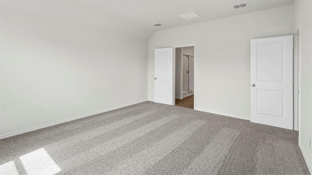 Spacious room featuring light gray carpeting, crisp white walls, and two white panel doors