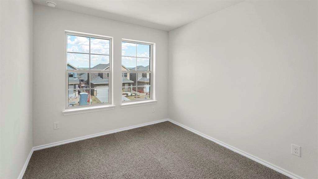 Bedroom featuring two windows, neutral gray carpeting, white baseboards, and light-colored wall paint