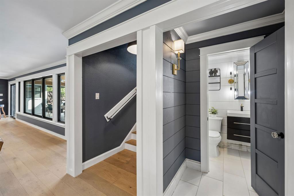 Hallway featuring neutral flooring, decorative wall treatments and access to the staircase and updated half bath.