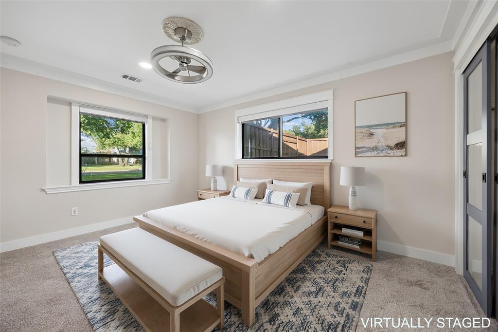 Bright guest bedroom with neutral finishes, recessed lighting, a modern ceiling fan, updated carpet and windows overlooking the front yard.