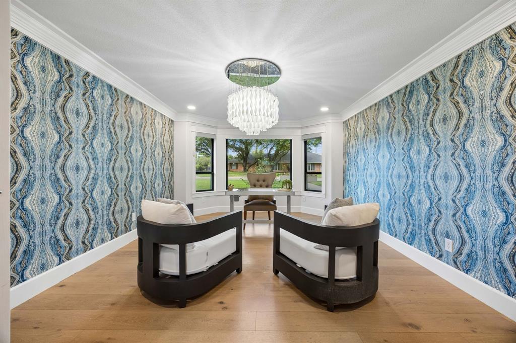 Stunning designer wallpaper, wood floors, a statement chandelier and a wall of windows overlooking the front yard with electric shades complete this inhome office.