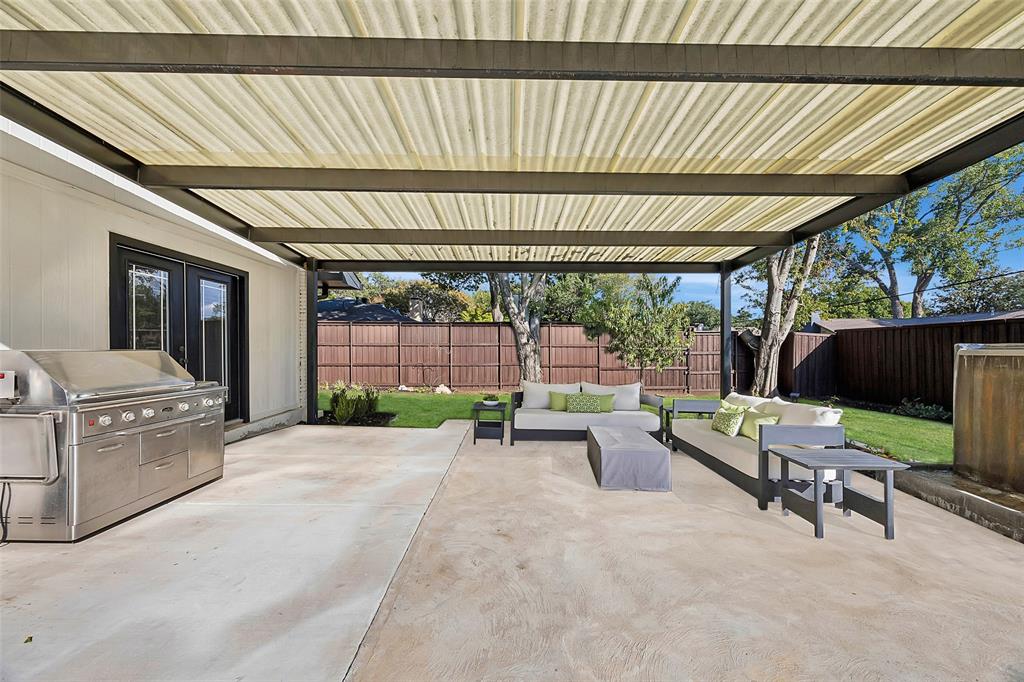 Spacious covered patio with french doors leading to the primary bedroom and extensive green space.