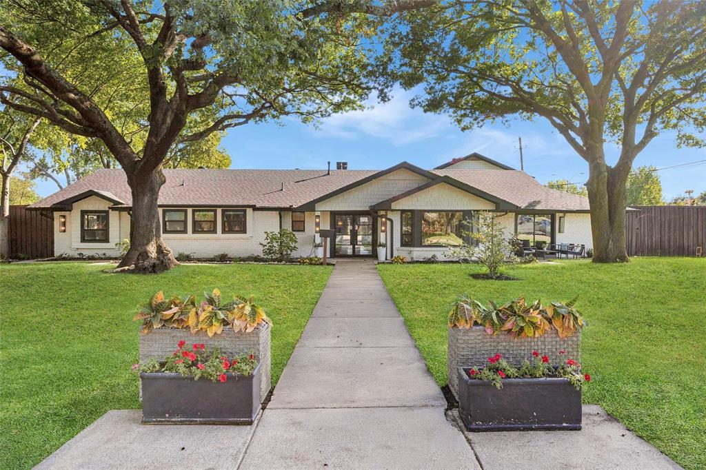 Beautifully updated single-story home with classic painted brick exterior, mature shade trees, inviting covered entry and expansive front lawn.