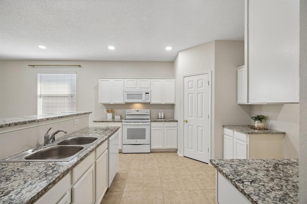 Storage and Counter Space Where You Need It – This angle showcases the kitchen’s abundant cabinetry and expansive granite surfaces, with a layout that provides dedicated areas for cooking, prep, storage, and serving.