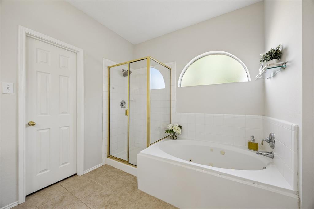 Soak, Shower, and Unwind – The primary bath includes a jetted tub and separate walk-in shower with ceramic tile surround, while the arched window adds natural light and architectural interest.