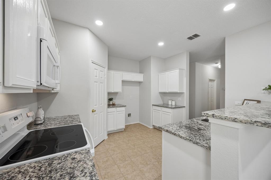 A Kitchen with Space to Work – Generous granite countertops, white cabinetry, an updated smooth-top range, and built-in microwave create a bright, functional kitchen with multiple work areas and plenty of room for meal prep.