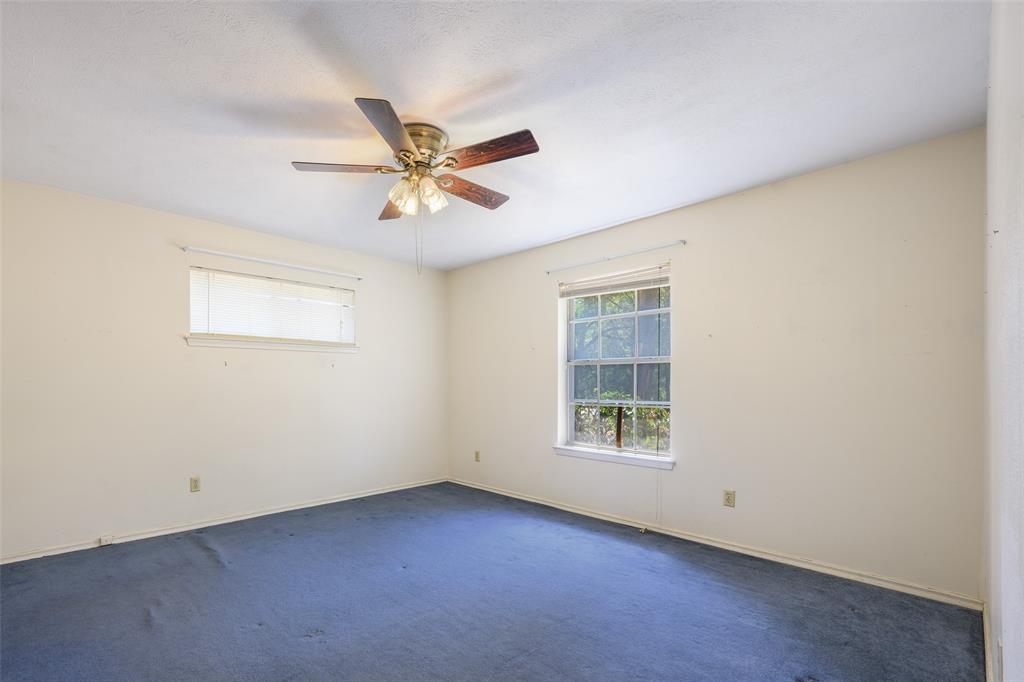 Blue carpeting with a window and a ceiling fan