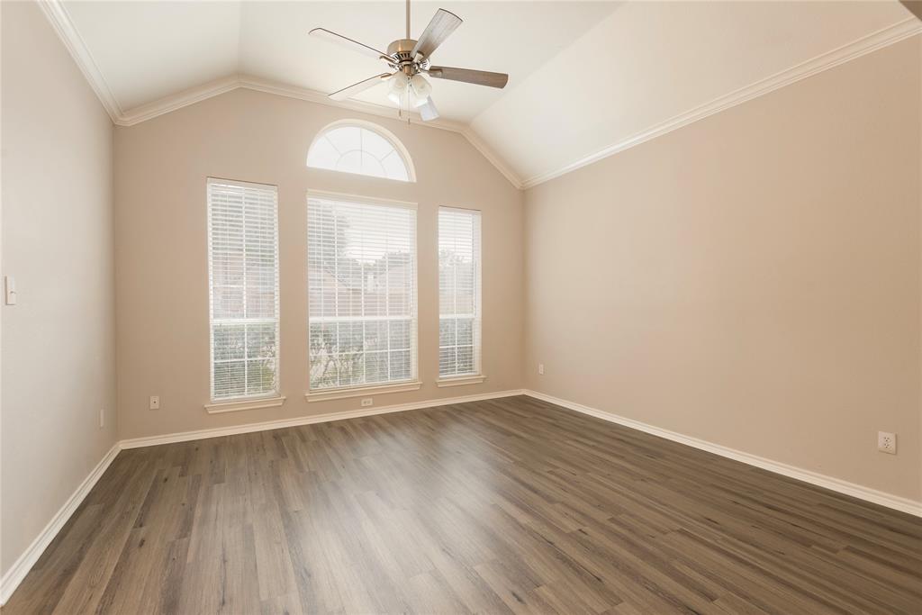 Spare room with lofted ceiling, crown molding, and dark wood-type flooring