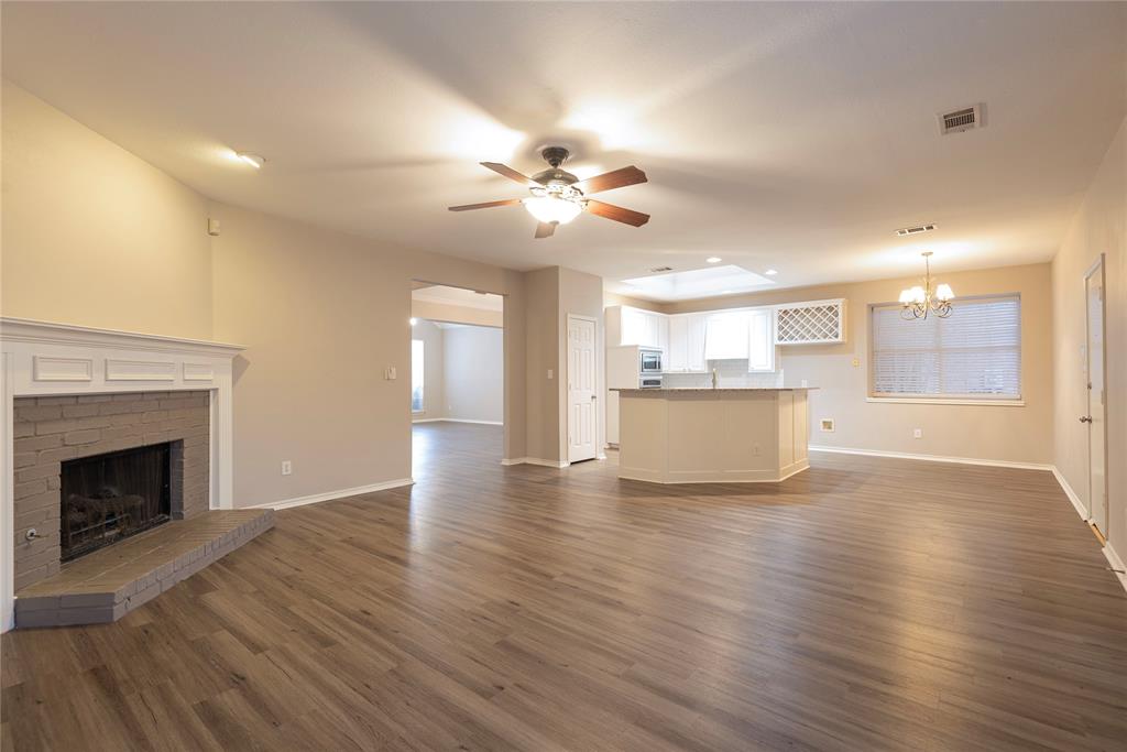 Unfurnished living room with a fireplace, ceiling fan with notable chandelier, and dark wood-type flooring