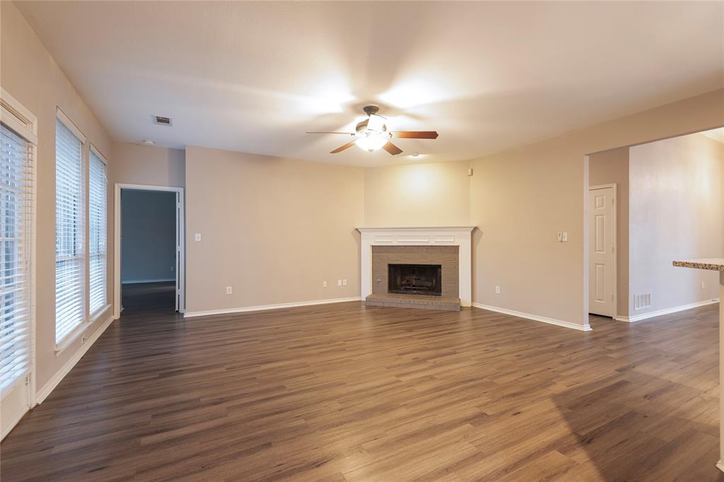 Unfurnished living room with dark hardwood / wood-style floors, ceiling fan, and a brick fireplace