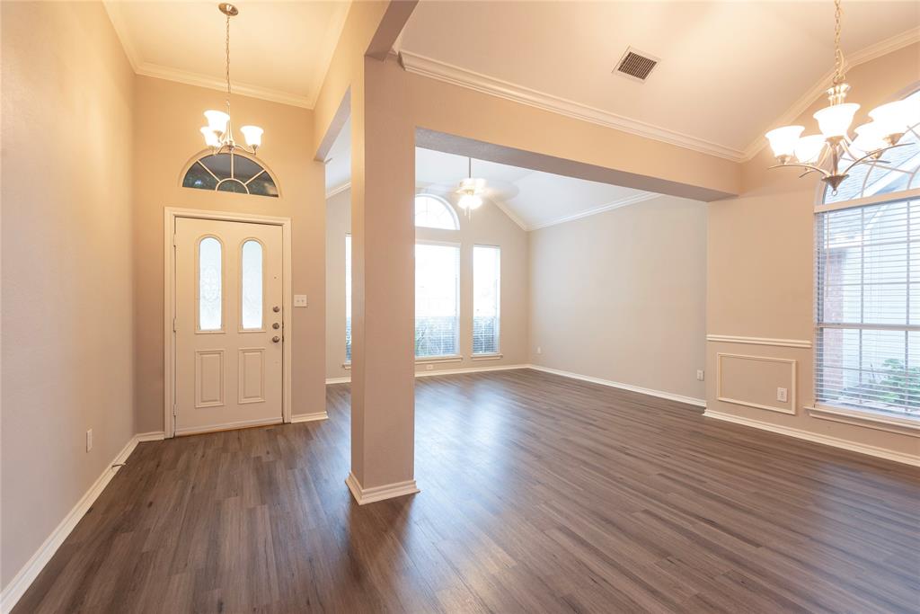 Entryway featuring ceiling fan with notable chandelier, crown molding, and dark wood-type flooring