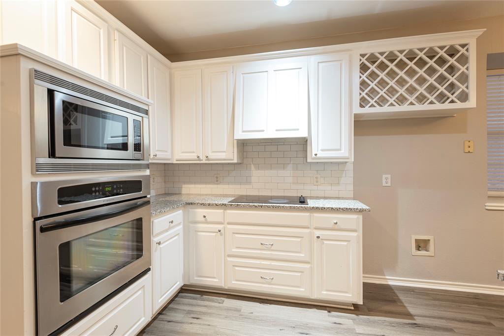 Kitchen featuring white cabinetry, light wood-type flooring, stainless steel appliances, and tasteful backsplash