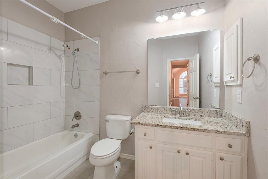 Full bathroom featuring tile patterned flooring, tiled shower / bath combo, toilet, and vanity