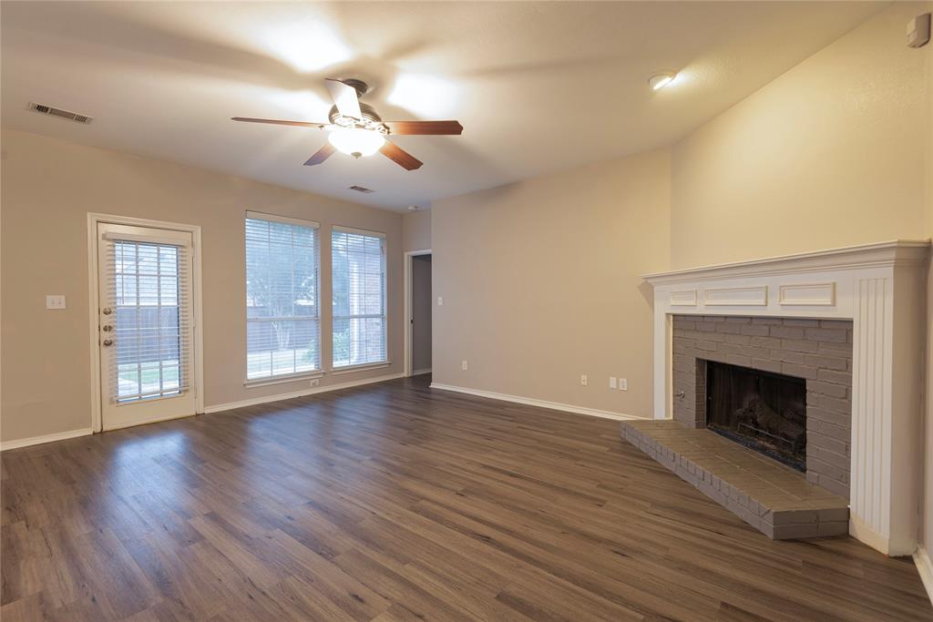 Unfurnished living room with dark hardwood / wood-style floors, ceiling fan, and a brick fireplace