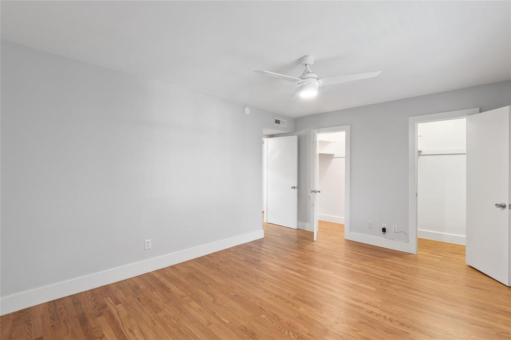 Unfurnished bedroom with a spacious closet, light wood-style flooring, and ceiling fan