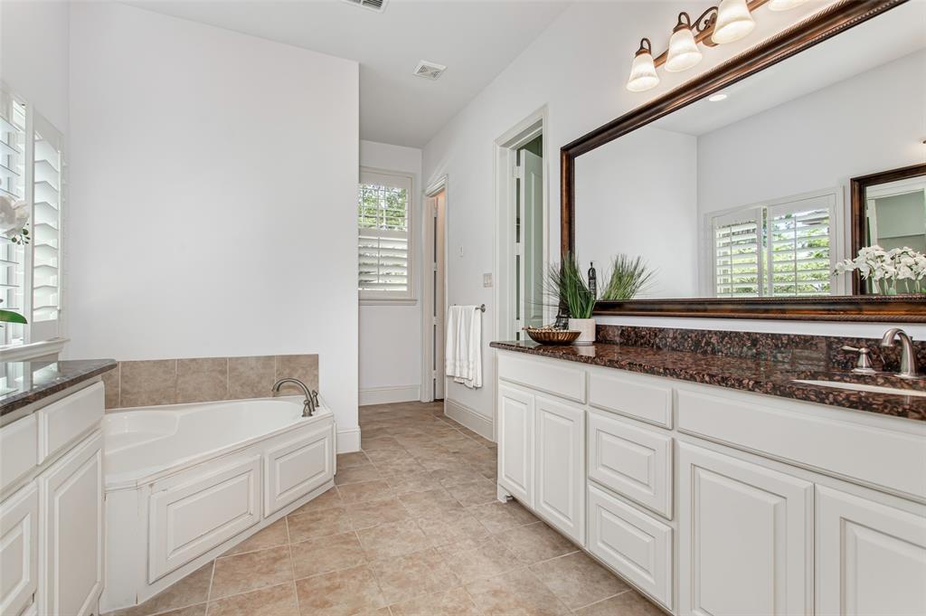 Dual vanity with granite countertops, integrated sink, and wall-mounted mirror