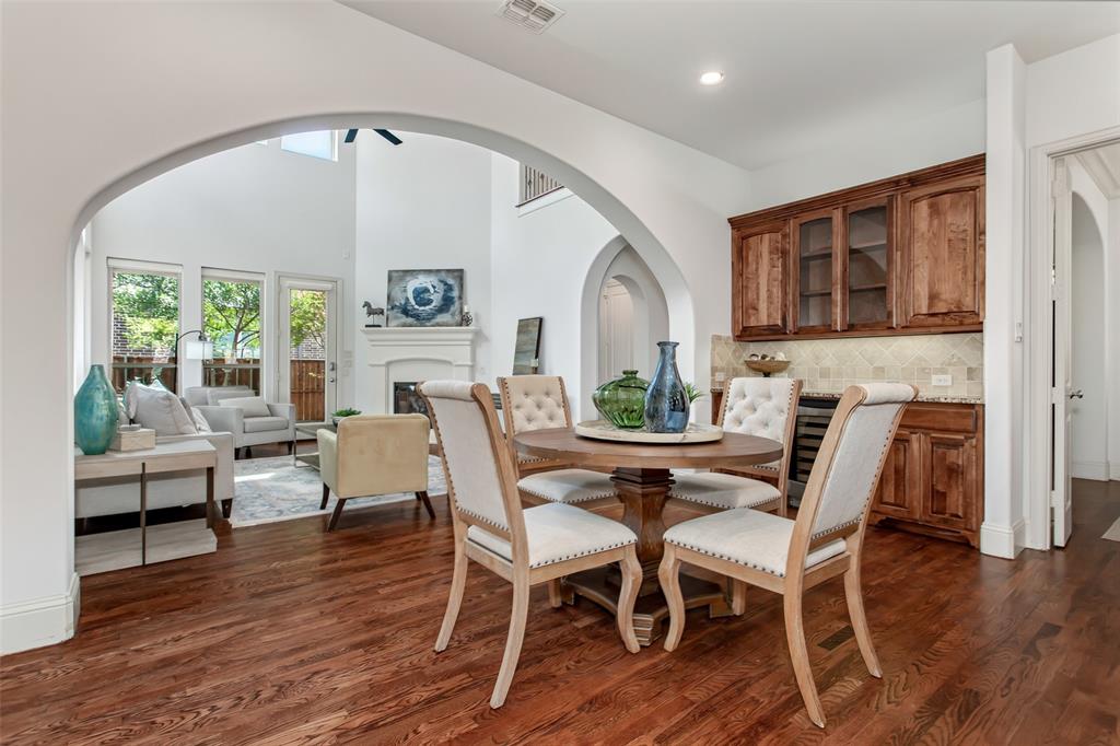 Arched entryways, wood-finish flooring, built-in wet bar with cabinetry, and a fireplace in the living area