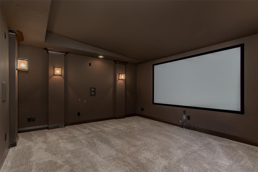 Media room featuring a large projector screen, wall sconces, recessed lighting, and carpeted flooring
