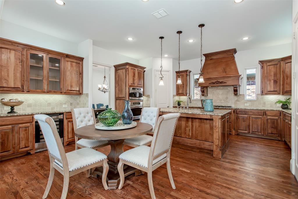 Hardwood flooring, custom wood cabinetry, granite countertops, tile backsplash, and recessed lighting