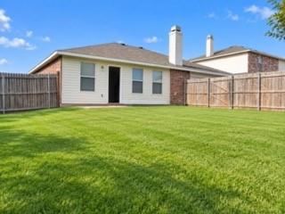Expansive backyard featuring a manicured lawn, full privacy fencing, and a red brick and siding exterior