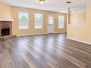 Wood-finish flooring throughout, brick fireplace with mantel, multiple windows with blinds, and recessed lighting
