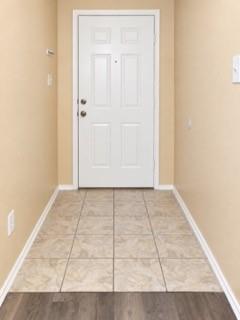 Entryway with tiled flooring, contrasting wood-finish flooring, and a paneled entry door