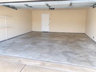 Spacious garage with light-toned walls, a durable concrete floor, and built-in shelving